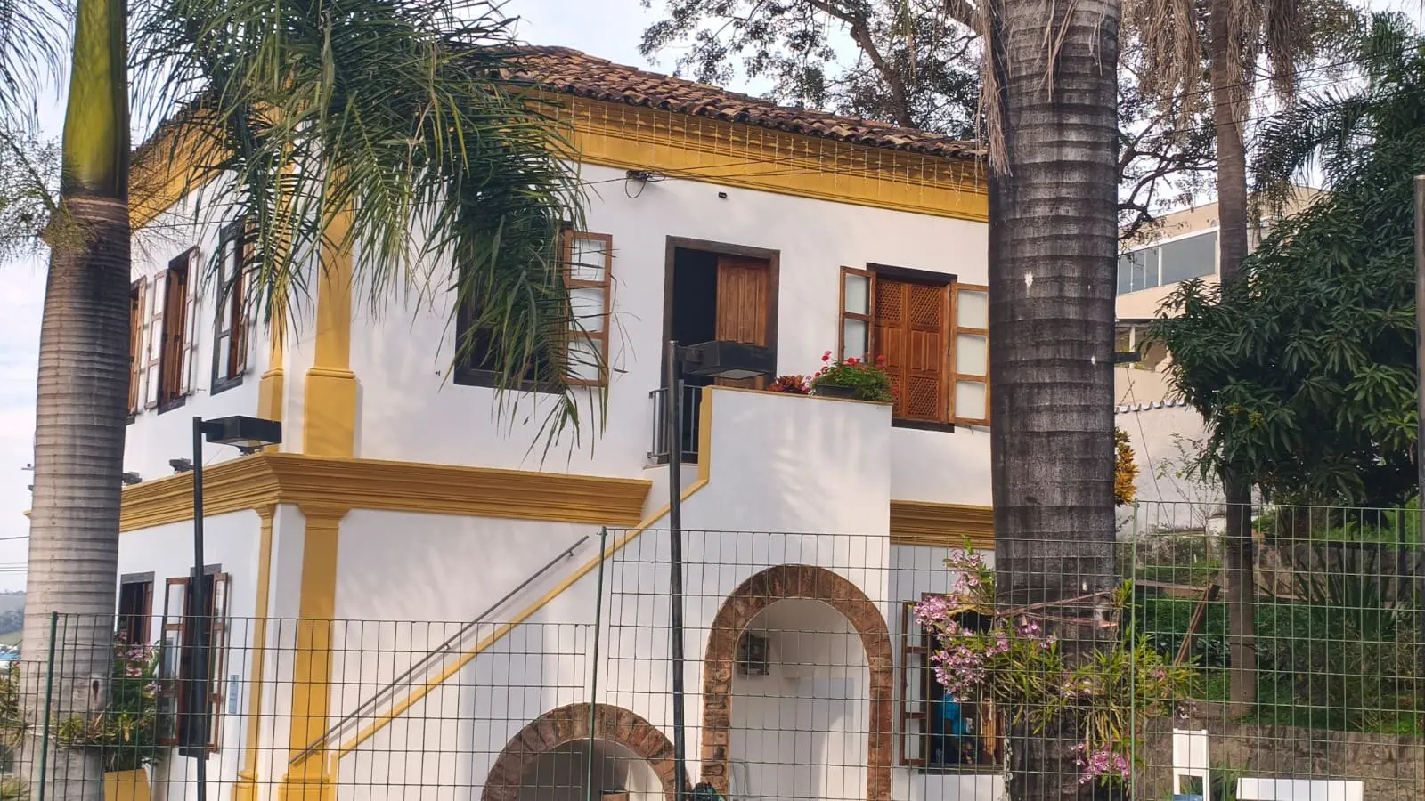 Lateral do casarão com escadaria externa e arco de tijolos aparentes