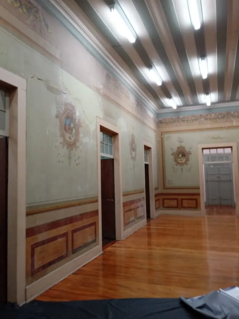 Sala com pinturas decorativas preservadas nas paredes e piso encerado