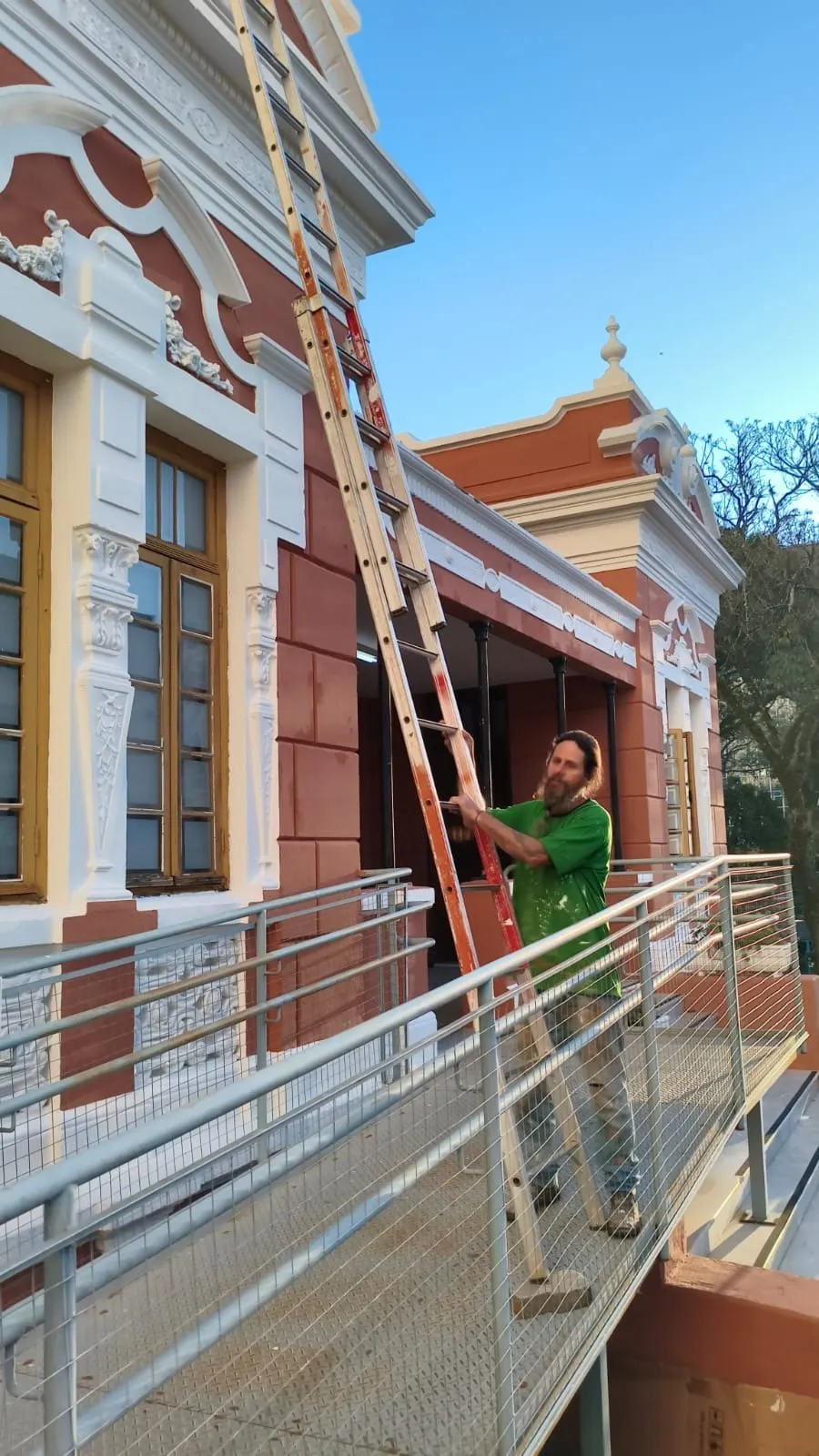 Pintor da Tico Pinturas em escada pintando a fachada junto à rampa