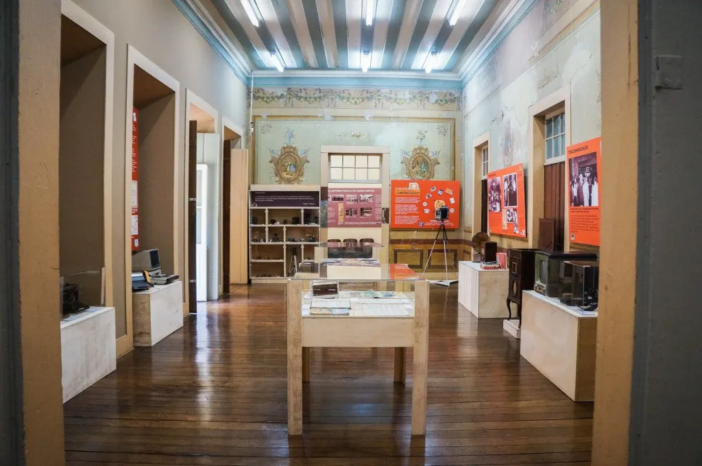 Sala de exposição com vitrines e forro listrado em madeira