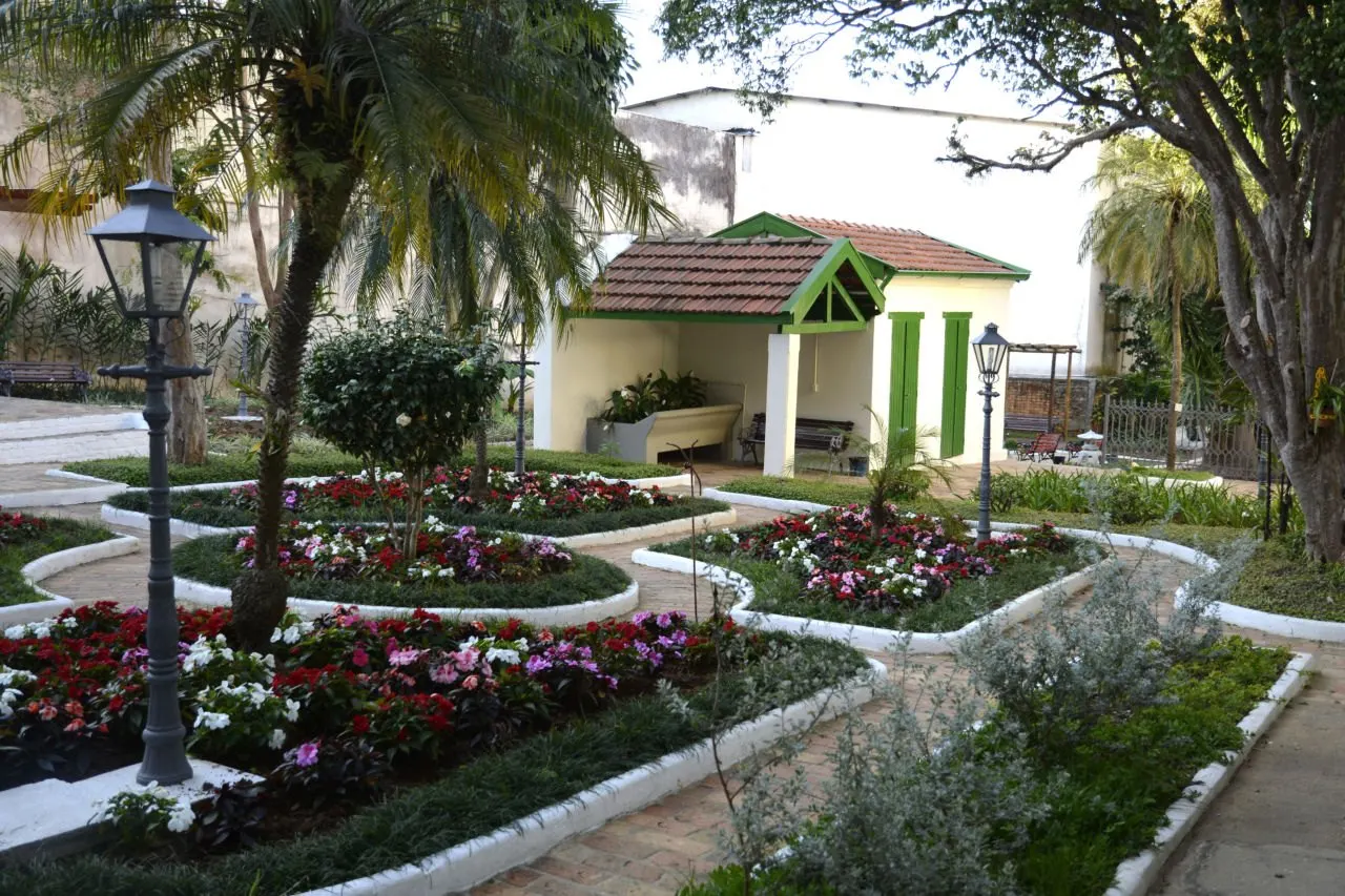 Jardim interno do Solar do Barão com canteiros e lampião