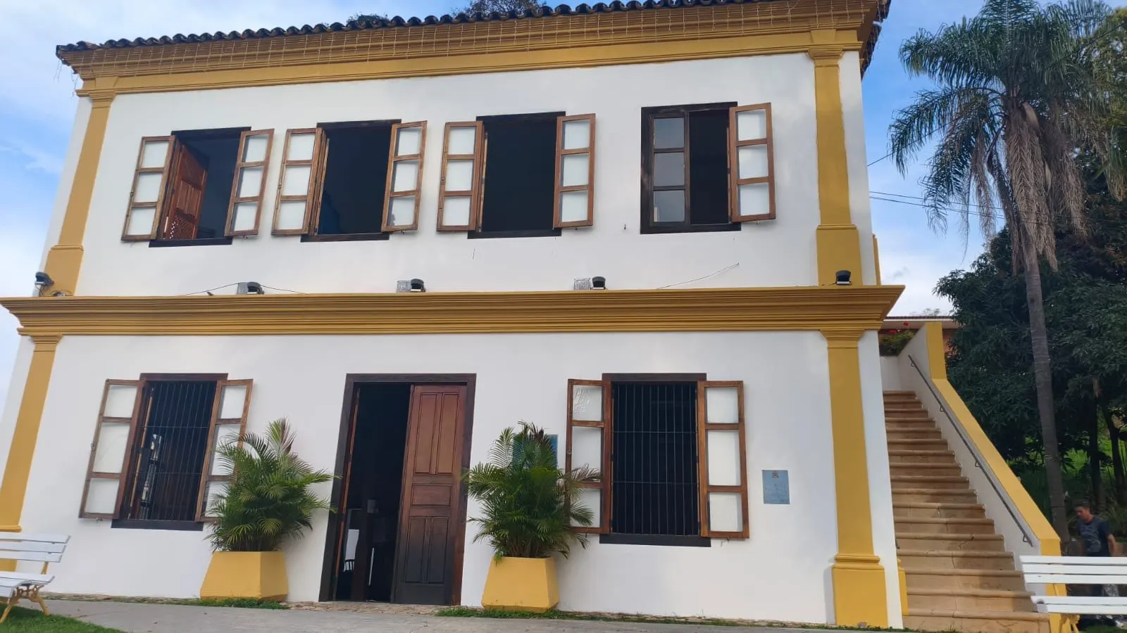 Fachada frontal com portas de madeira e vasos de plantas