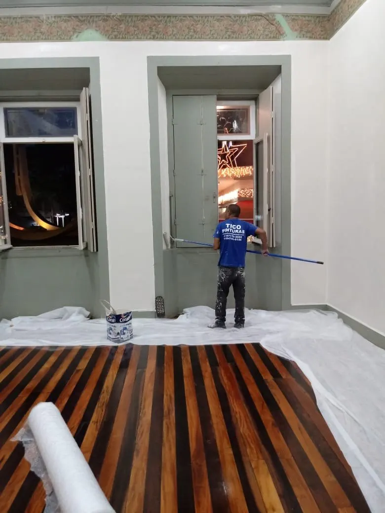 Pintor da Tico Pinturas pintando batentes de janela com o piso coberto por lona
