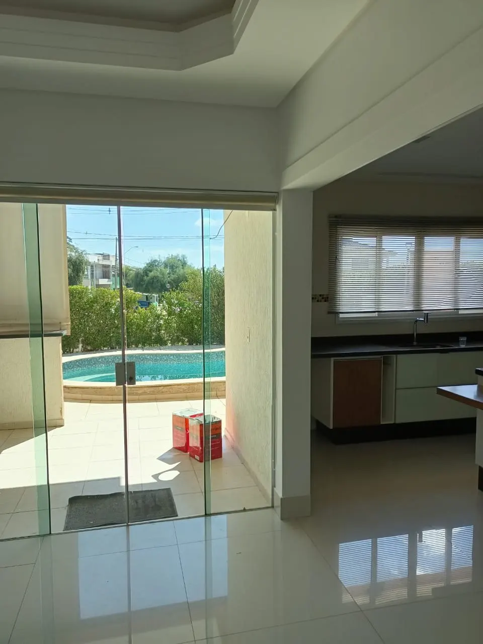 Sala integrada com vista para a piscina e paredes brancas recém-pintadas