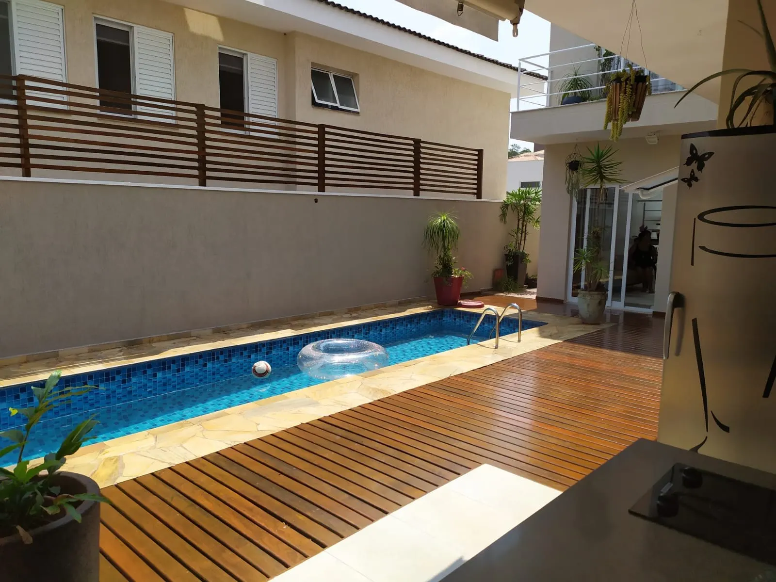 Área da piscina com deck de madeira e fachada dos fundos repintada